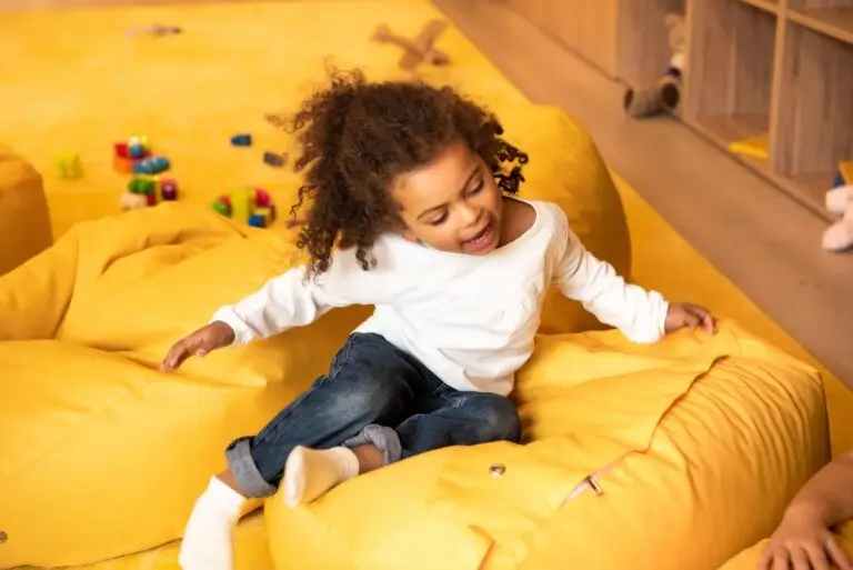 adorable african american kid sitting on bean bag chair in kindergarten