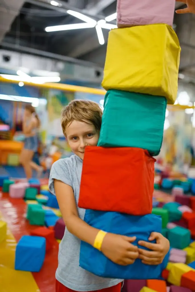 Happy little boy playing with soft cubes, playroom
